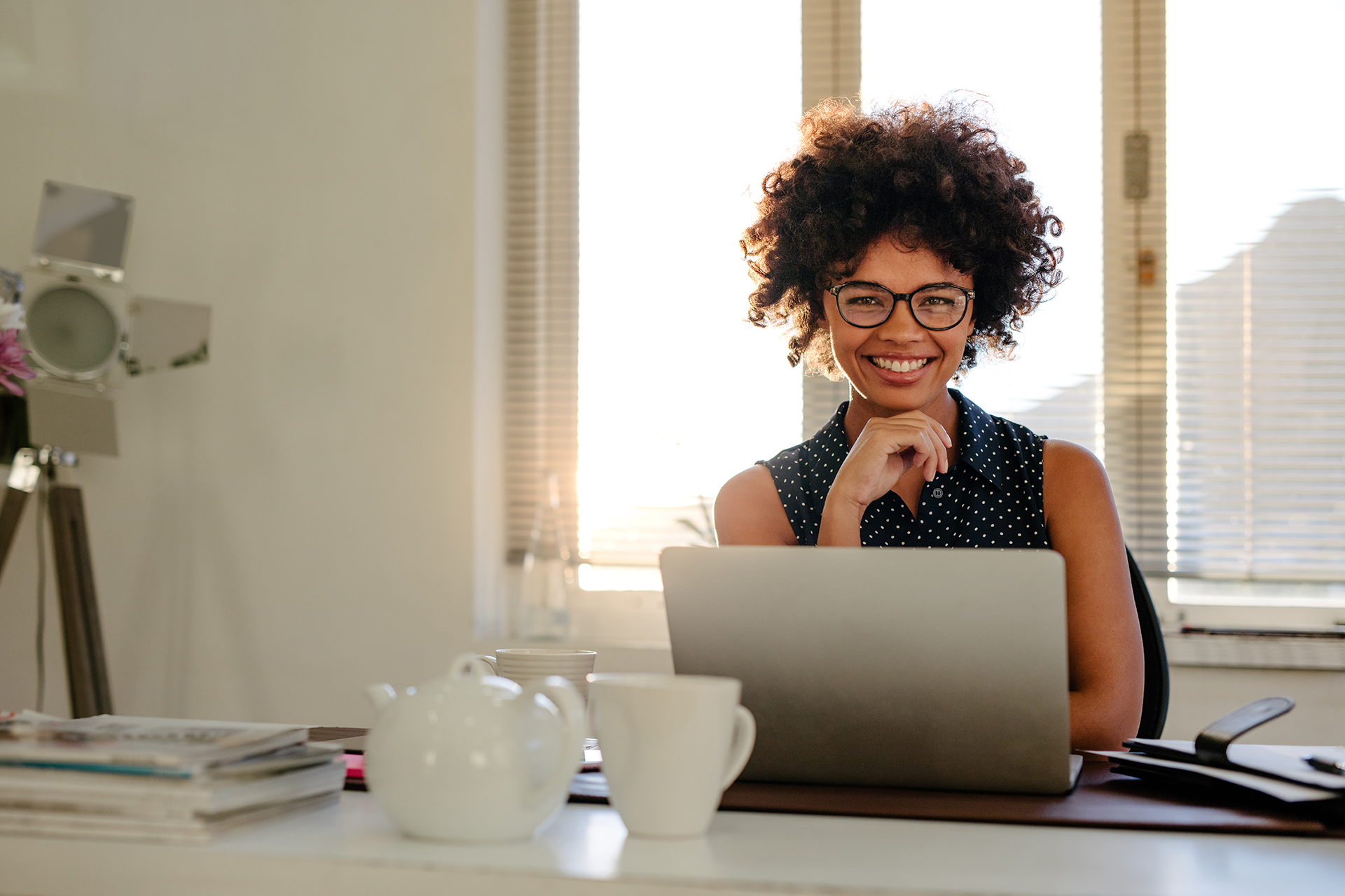 Background banner image of woman smiling in front of a laptop.